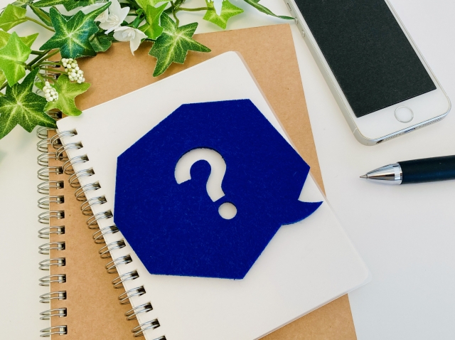 机の上にスマホとペンとはてなの吹き出し