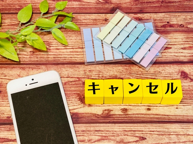 机の上に付箋とスマホとキャンセルと書かれた積み木がある