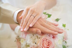 結婚指輪を付けた2人の手が重なっている
