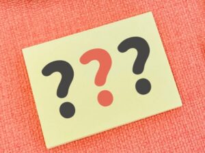 ピンクの背景に白い紙ではてなが3つ書かれている